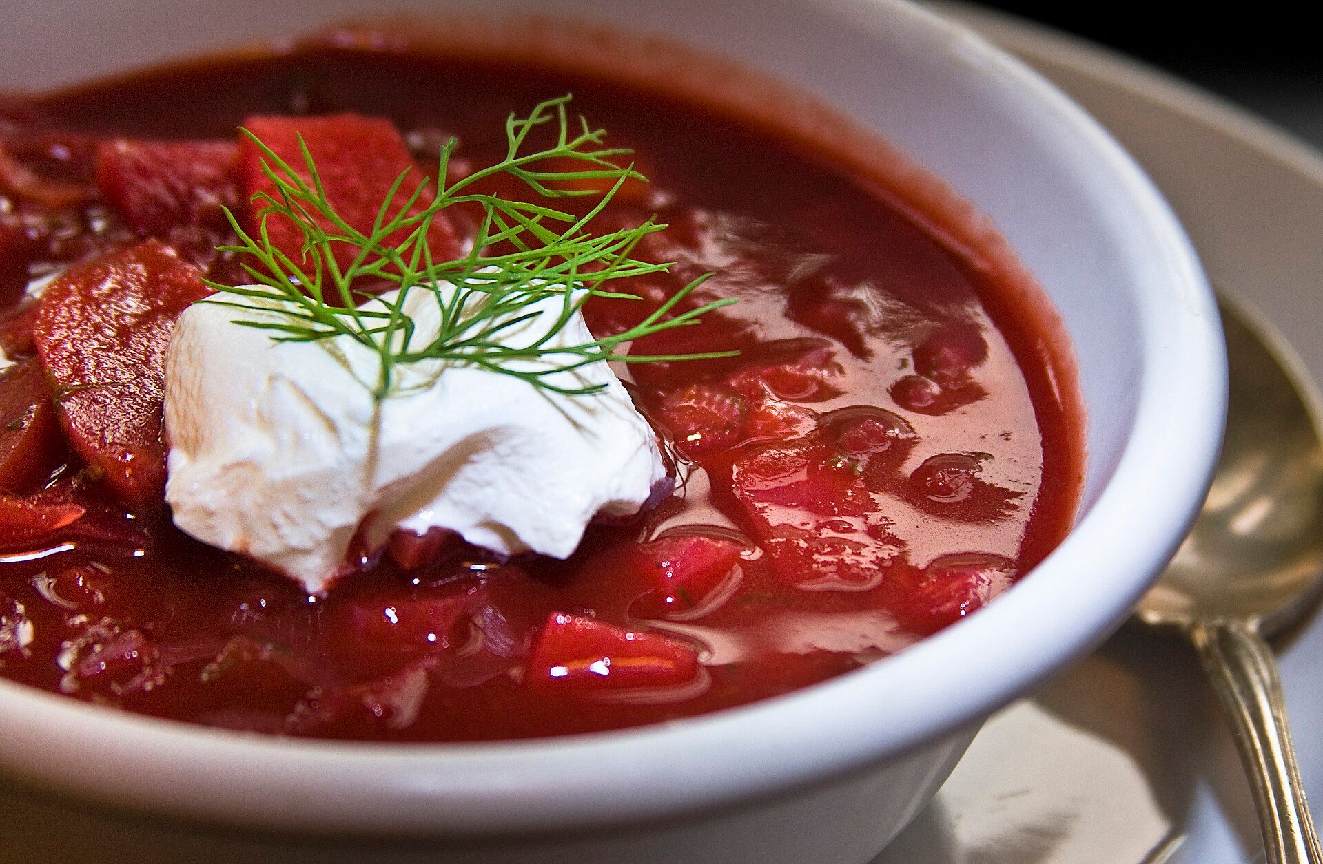 Bowl of borscht topped with sour cream and fresh dill.